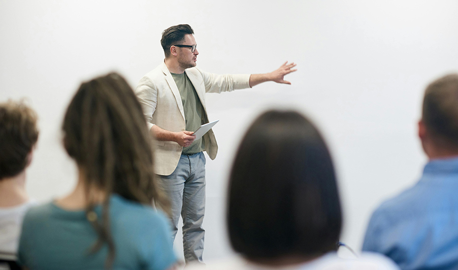 
			      Un docente imparte clase en un aula.			    
			  